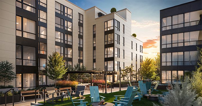 Modern multi-story residential buildings surrounding a courtyard with blue Adirondack chairs, landscaping, and trees at sunset.